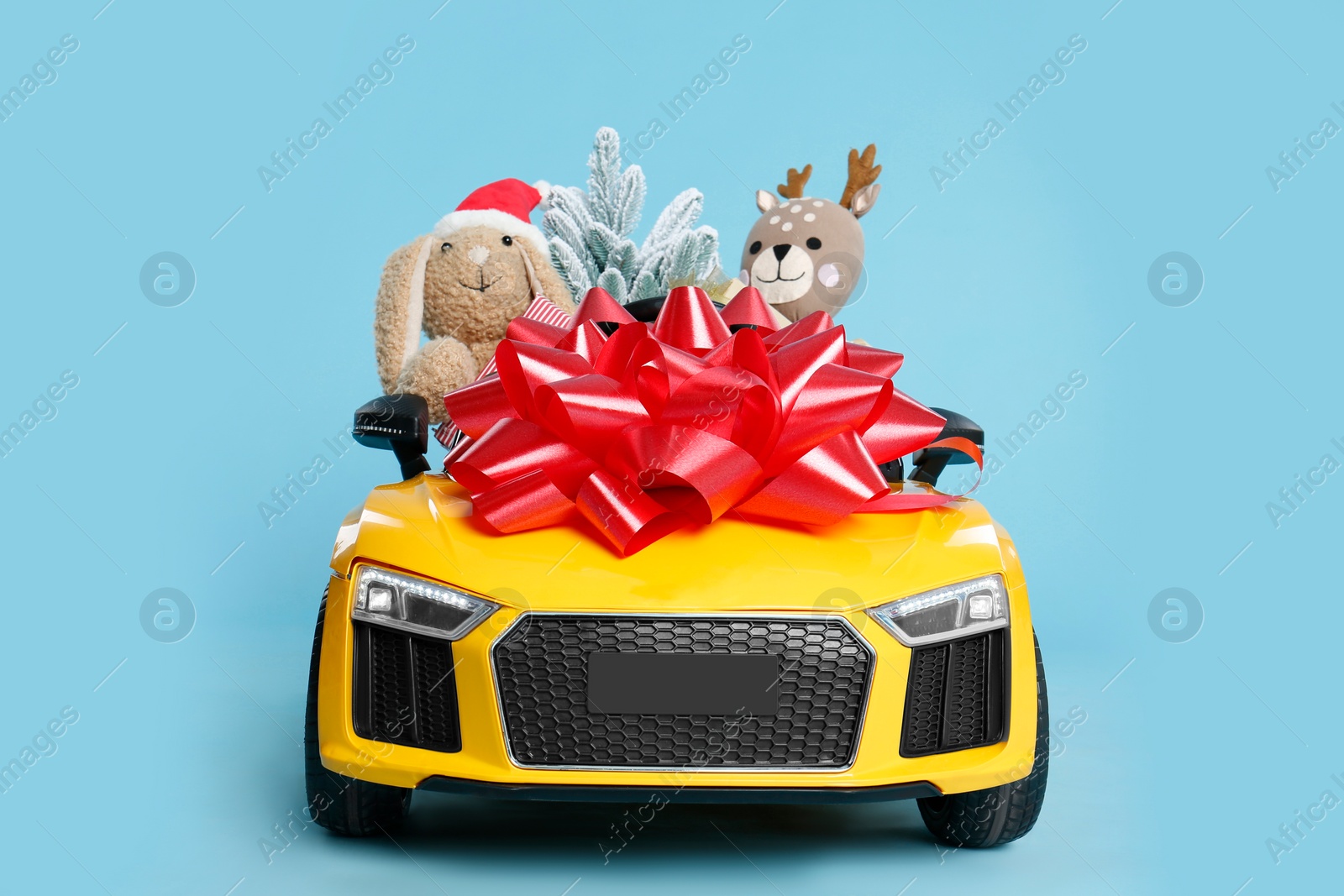 Photo of Child's electric car with toys and Christmas decor on light blue background