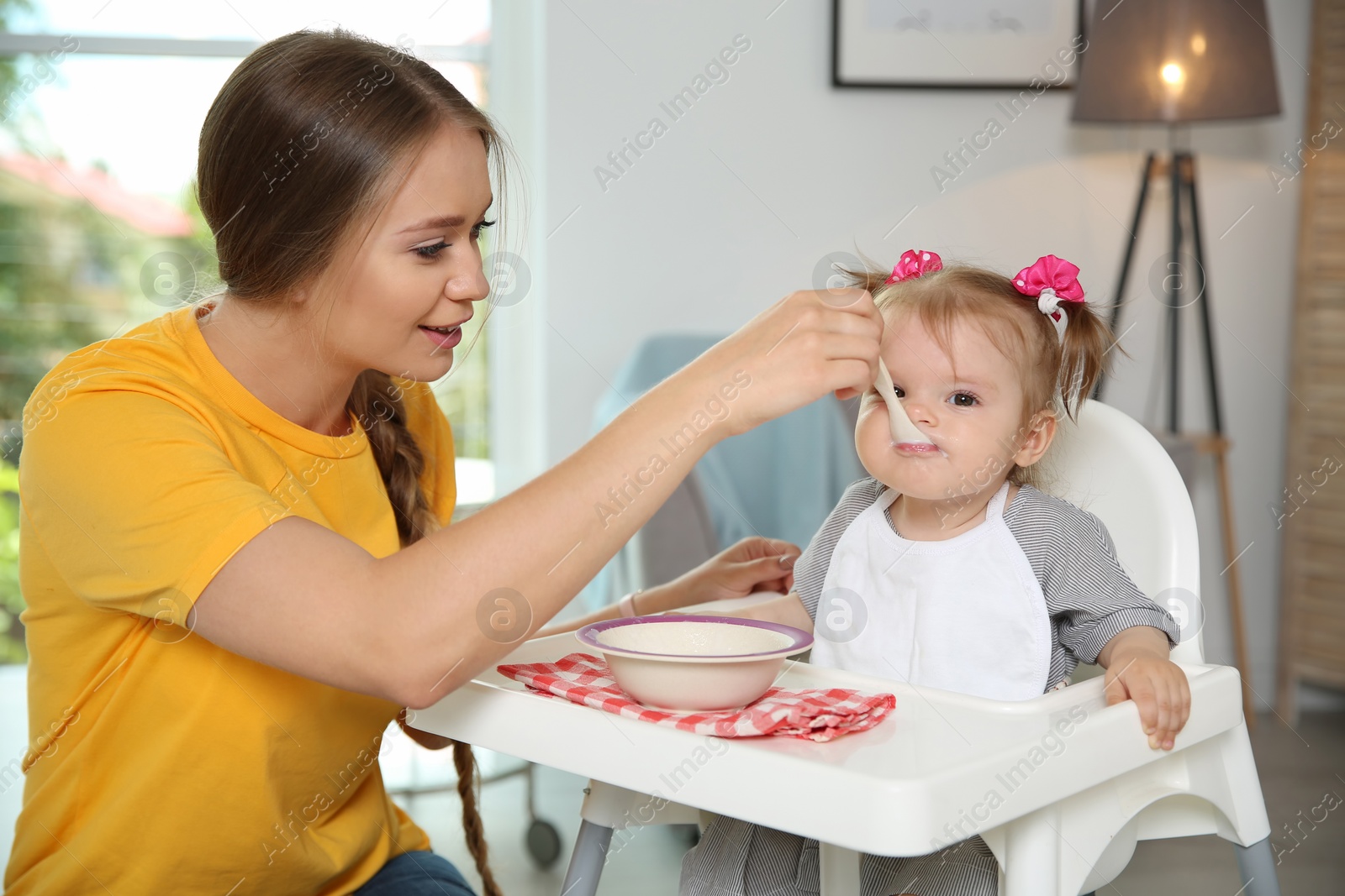 Photo of Mother feeding her cute little baby with healthy food at home