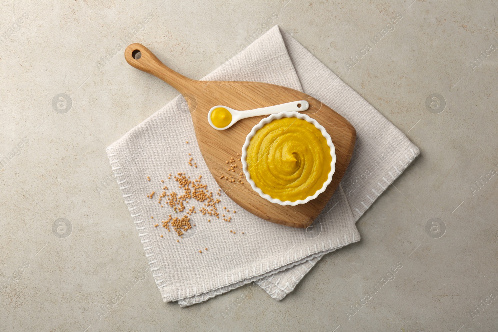 Photo of Tasty mustard sauce and dry seeds on light textured table, flat lay