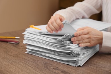 Photo of Woman stacking documents at wooden table indoors, closeup