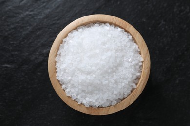 Photo of Organic white salt in bowl on black table, top view