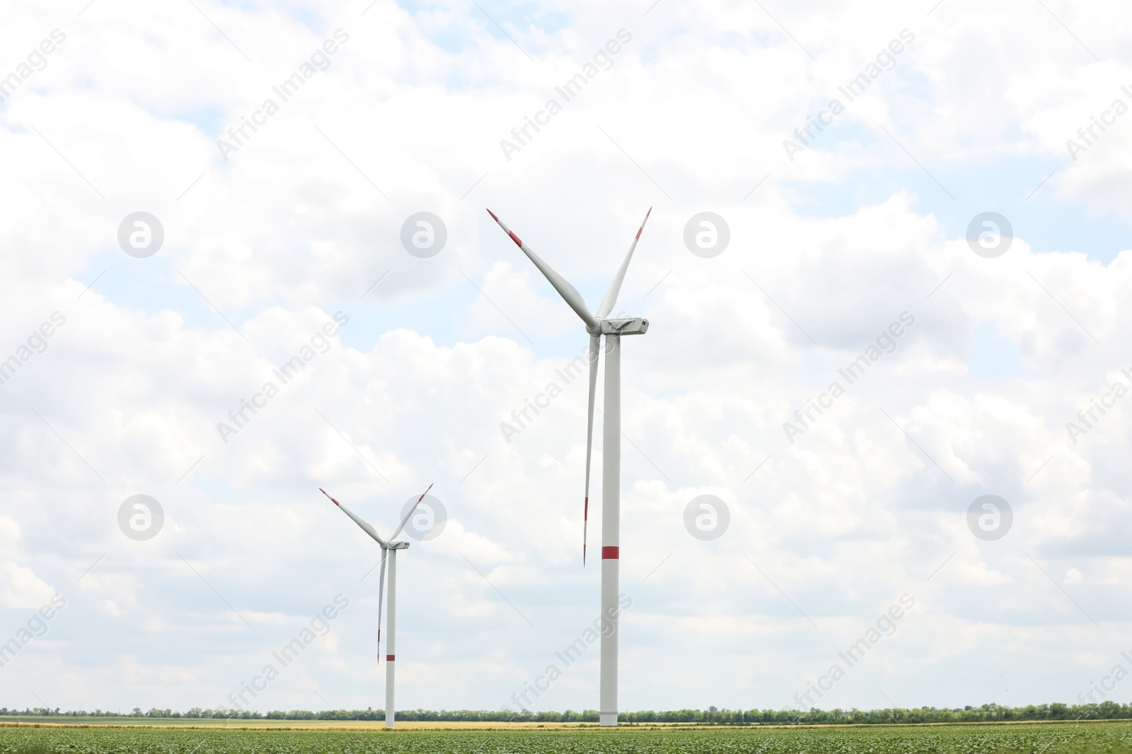 Photo of Modern wind turbines in field on cloudy day. Alternative energy source