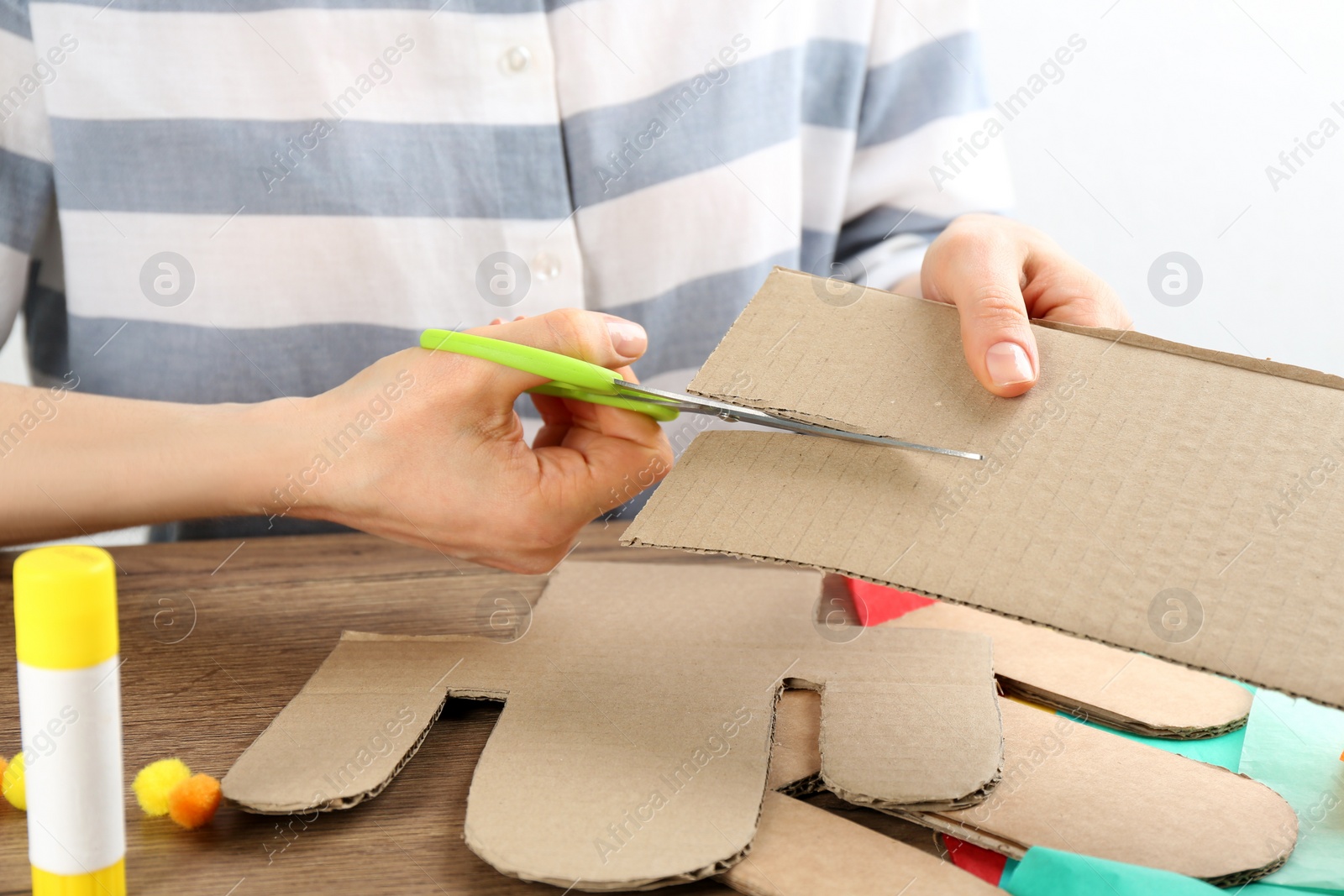 Photo of Woman making cardboard cactus at wooden table, closeup. Pinata DIY