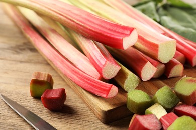 Many cut rhubarb stalks on wooden table, closeup