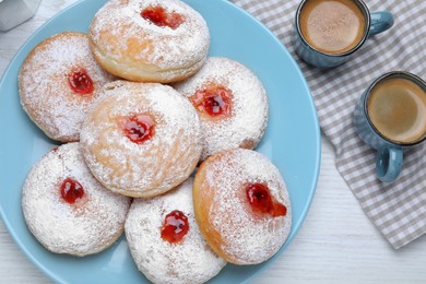 Delicious jam donuts served with coffee on white wooden table, flat lay