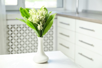 Vase with beautiful lily of the valley bouquet on table in room, space for text