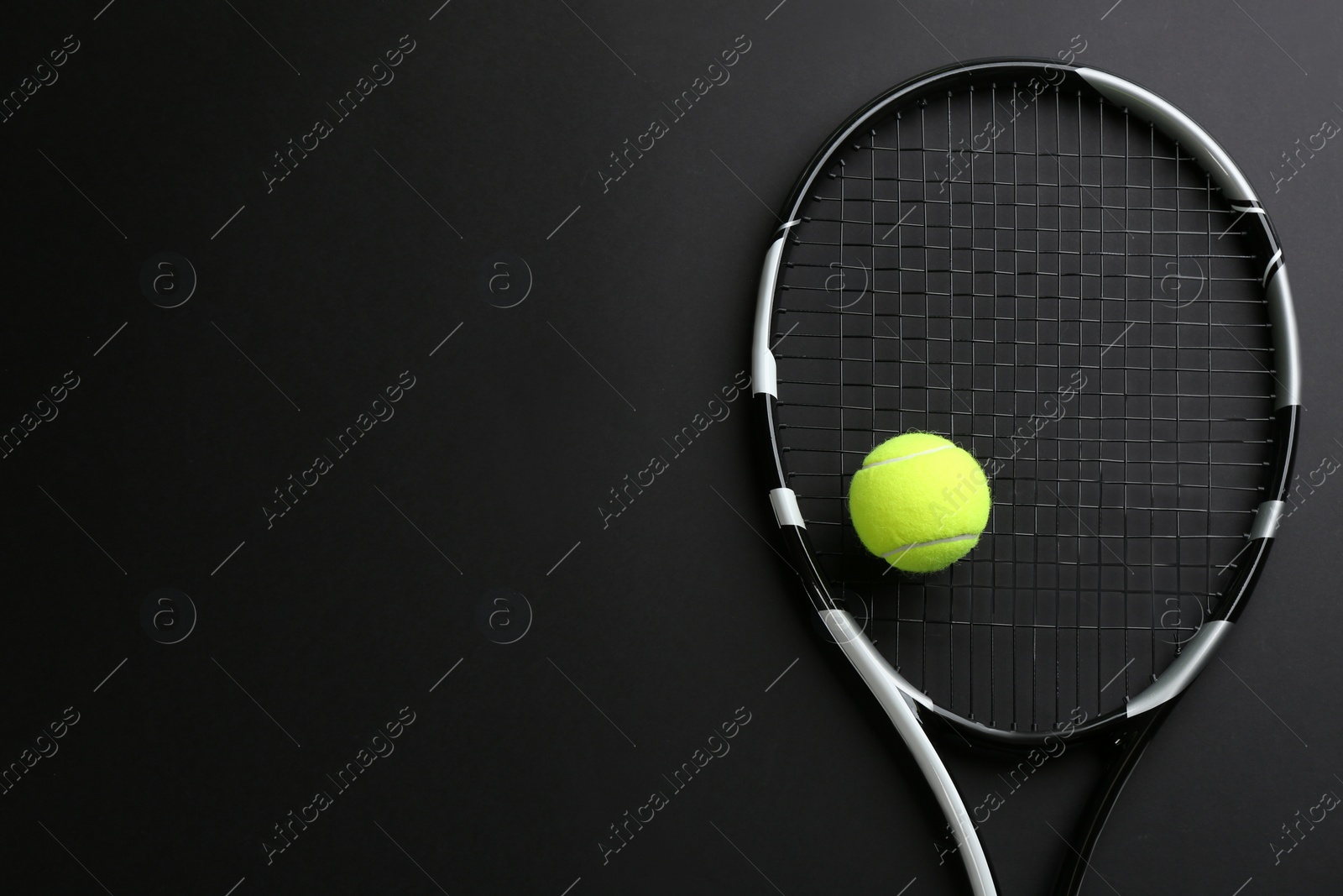 Photo of Tennis racket and ball on black background, top view. Space for text