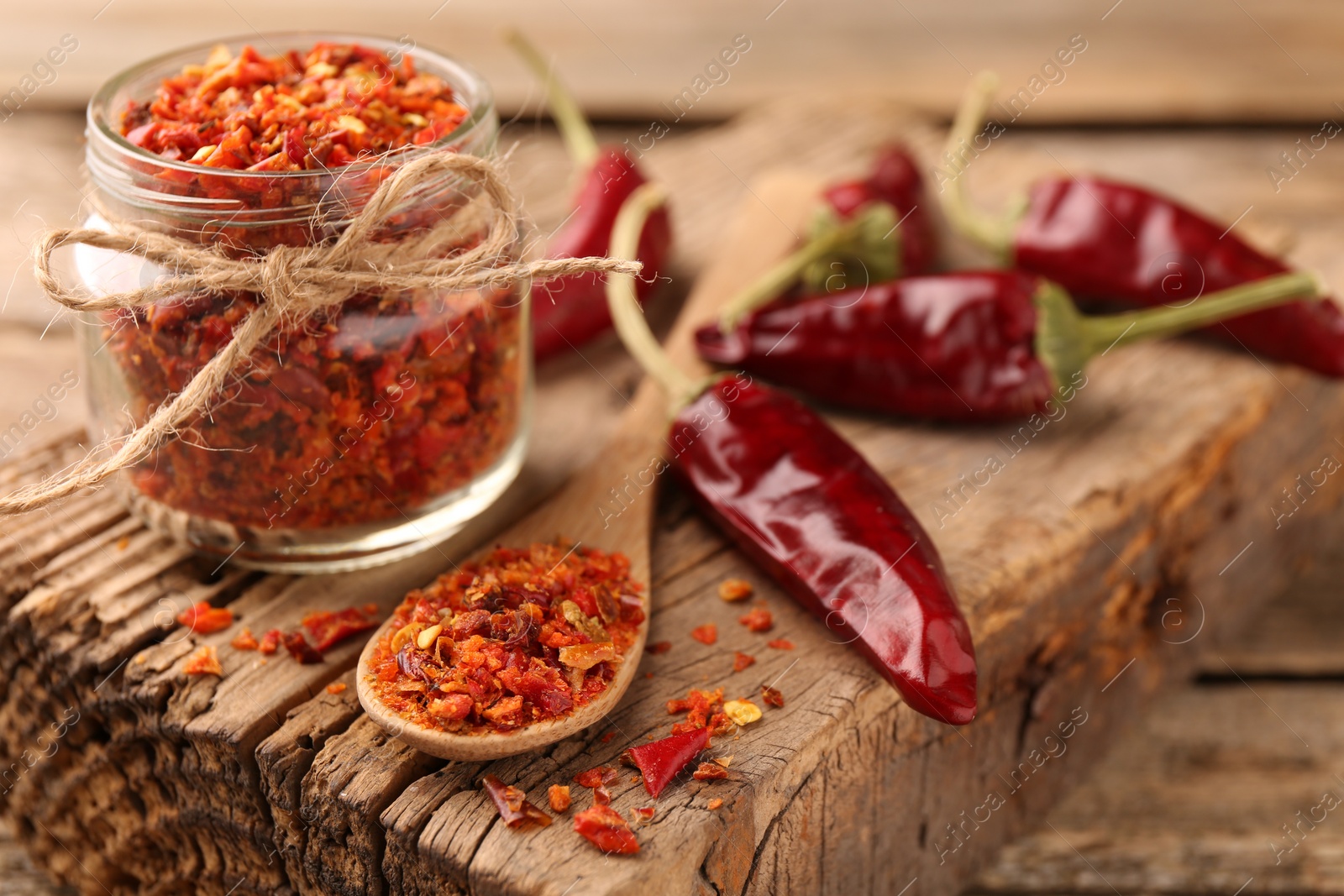 Photo of Chili pepper flakes and pods on wooden table, closeup