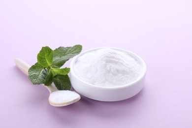 Photo of Sweet powdered fructose and mint leaves on light purple background