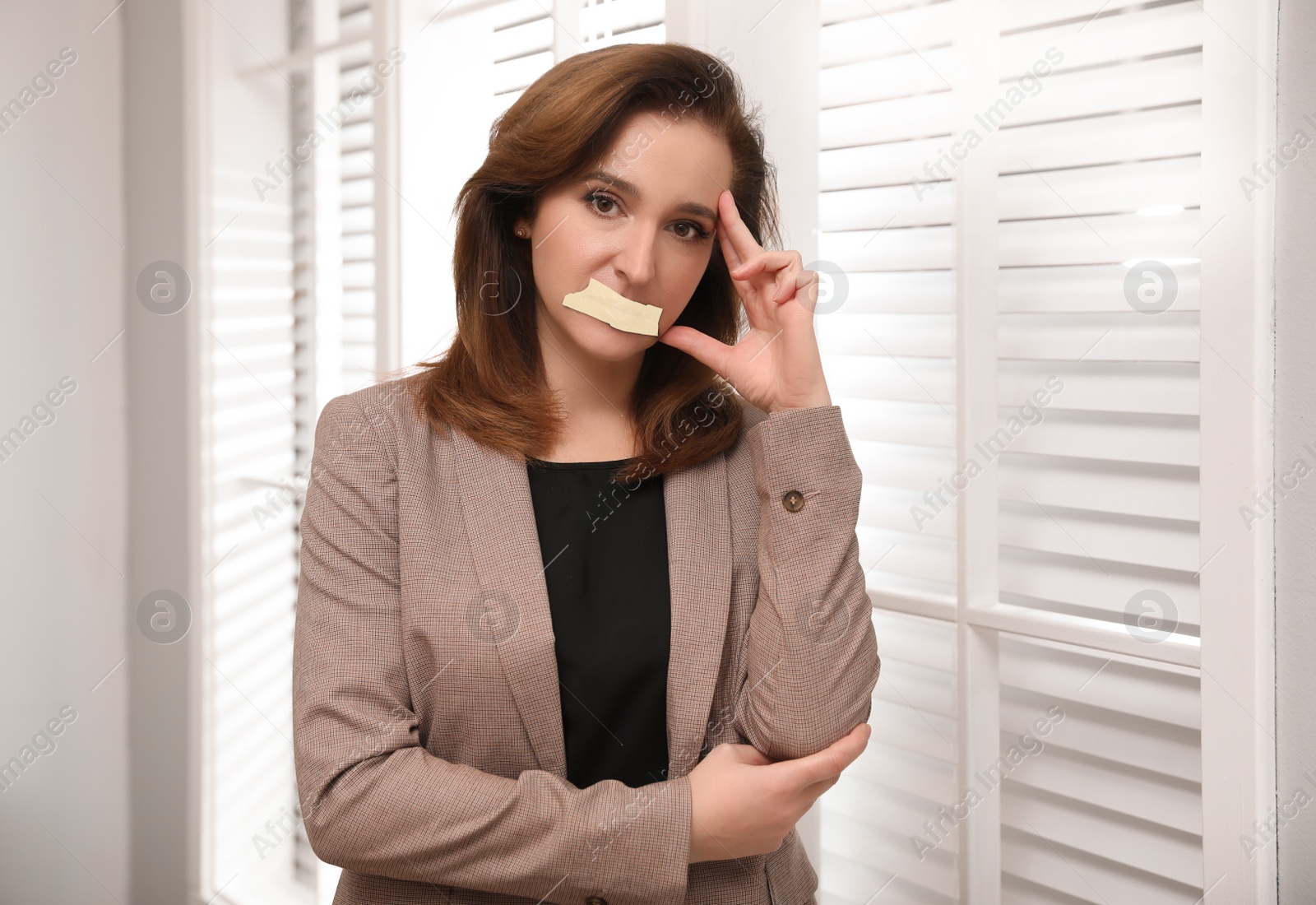 Image of Mature woman with taped mouth in office. Speech censorship