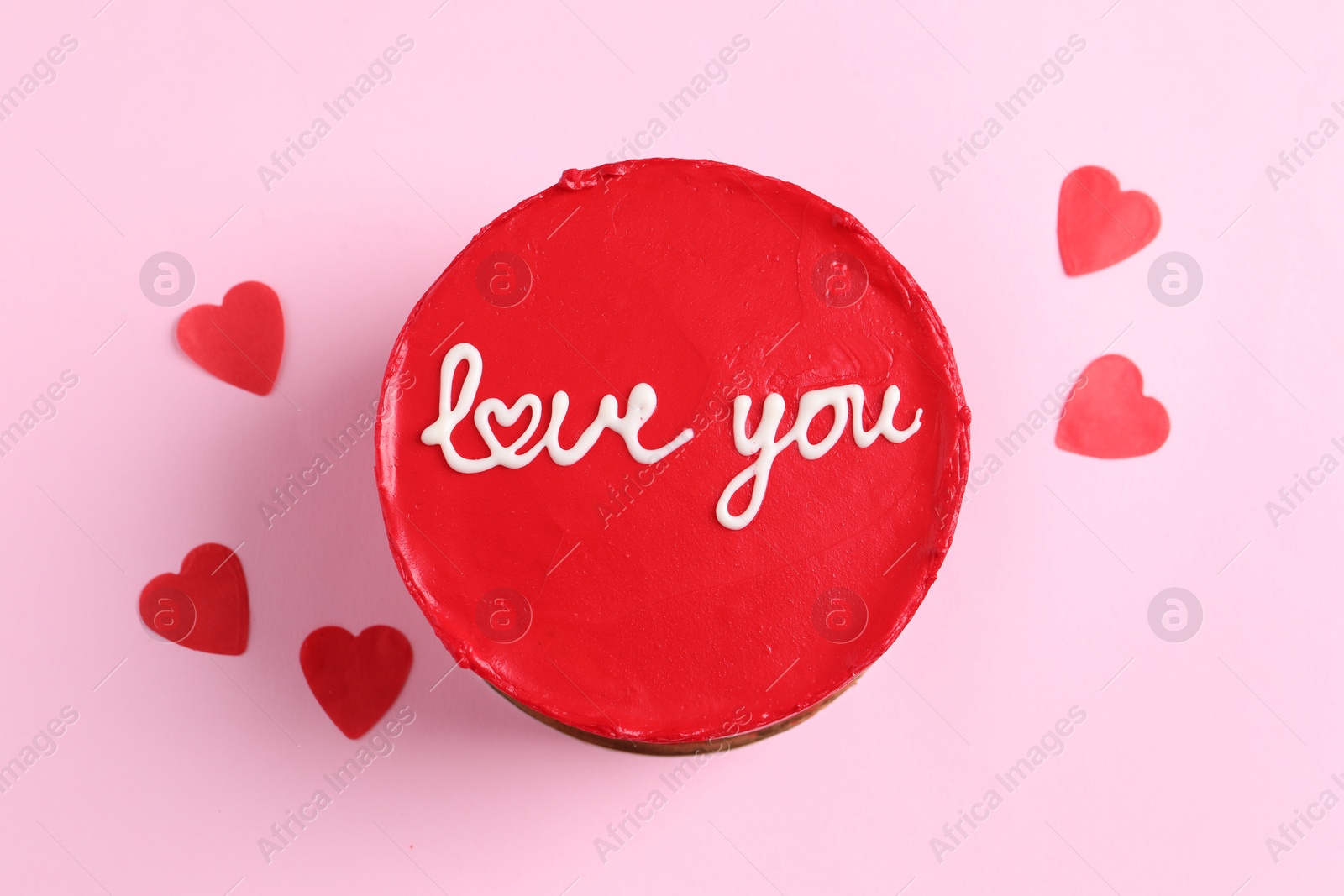 Photo of Bento cake with text Love You and paper hearts on pink table, top view. St. Valentine's day surprise