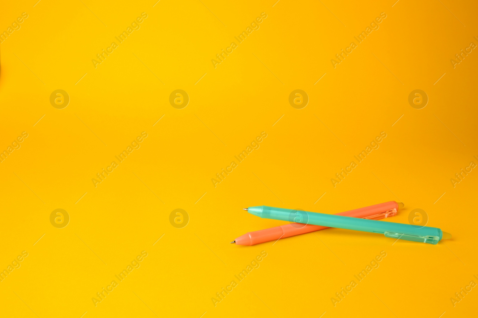 Photo of Two erasable pens on yellow background. Space for text