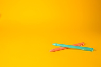 Photo of Two erasable pens on yellow background. Space for text