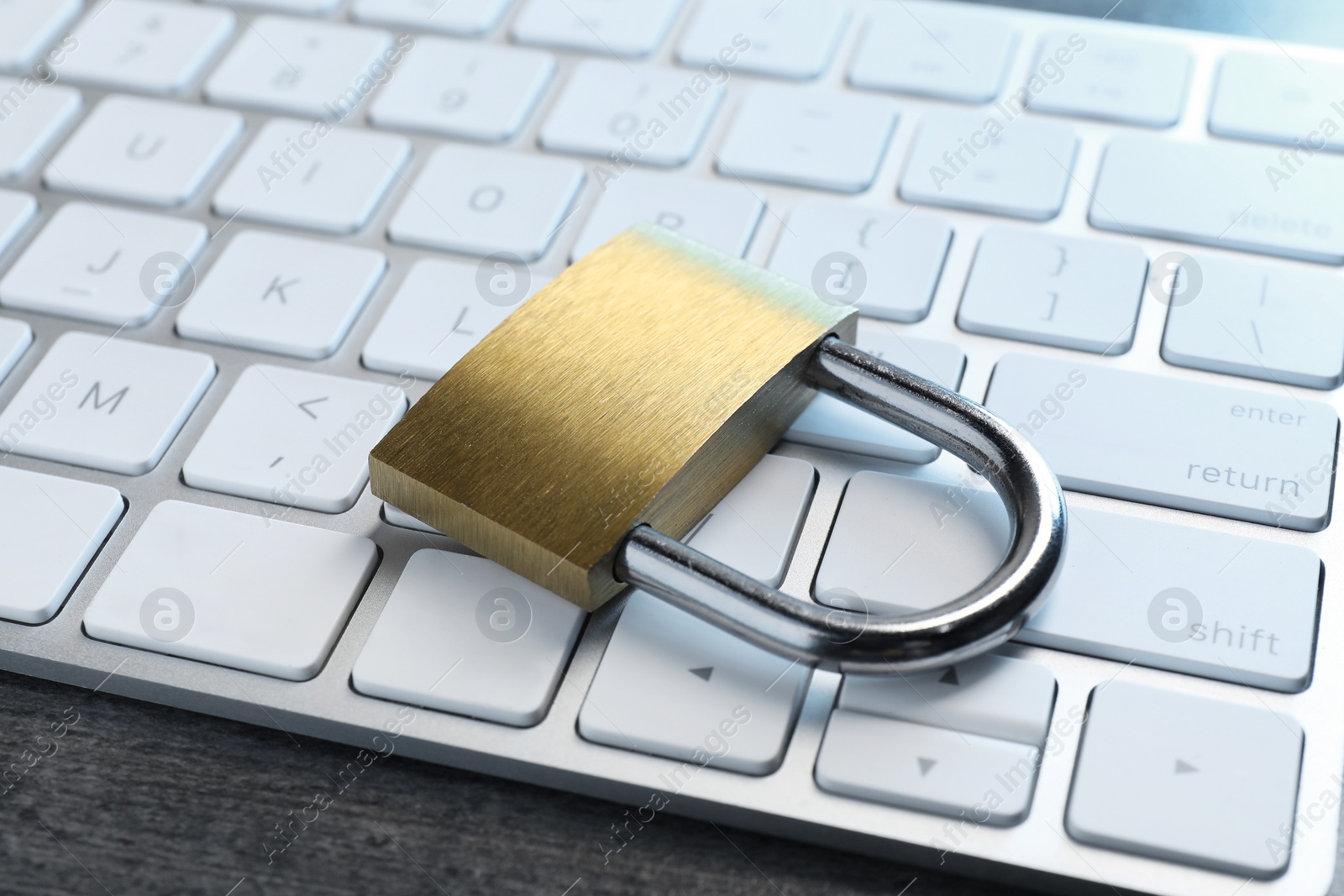 Photo of Cyber security. Metal padlock and keyboard on grey table, closeup