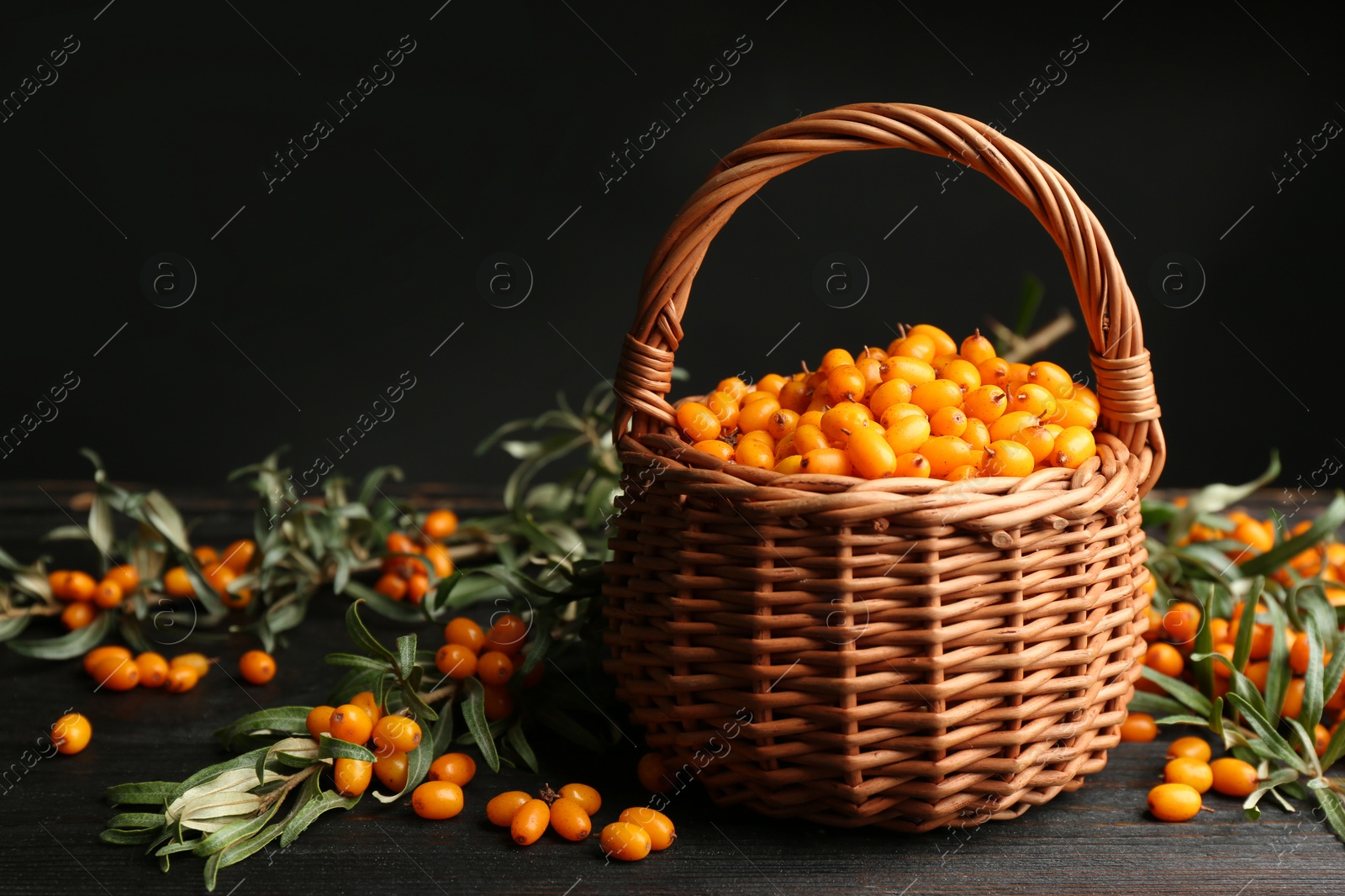 Photo of Ripe sea buckthorn berries on black wooden table