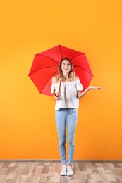 Woman with red umbrella near color wall