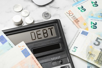 Image of Calculator with word Debt and money on white marble table, closeup