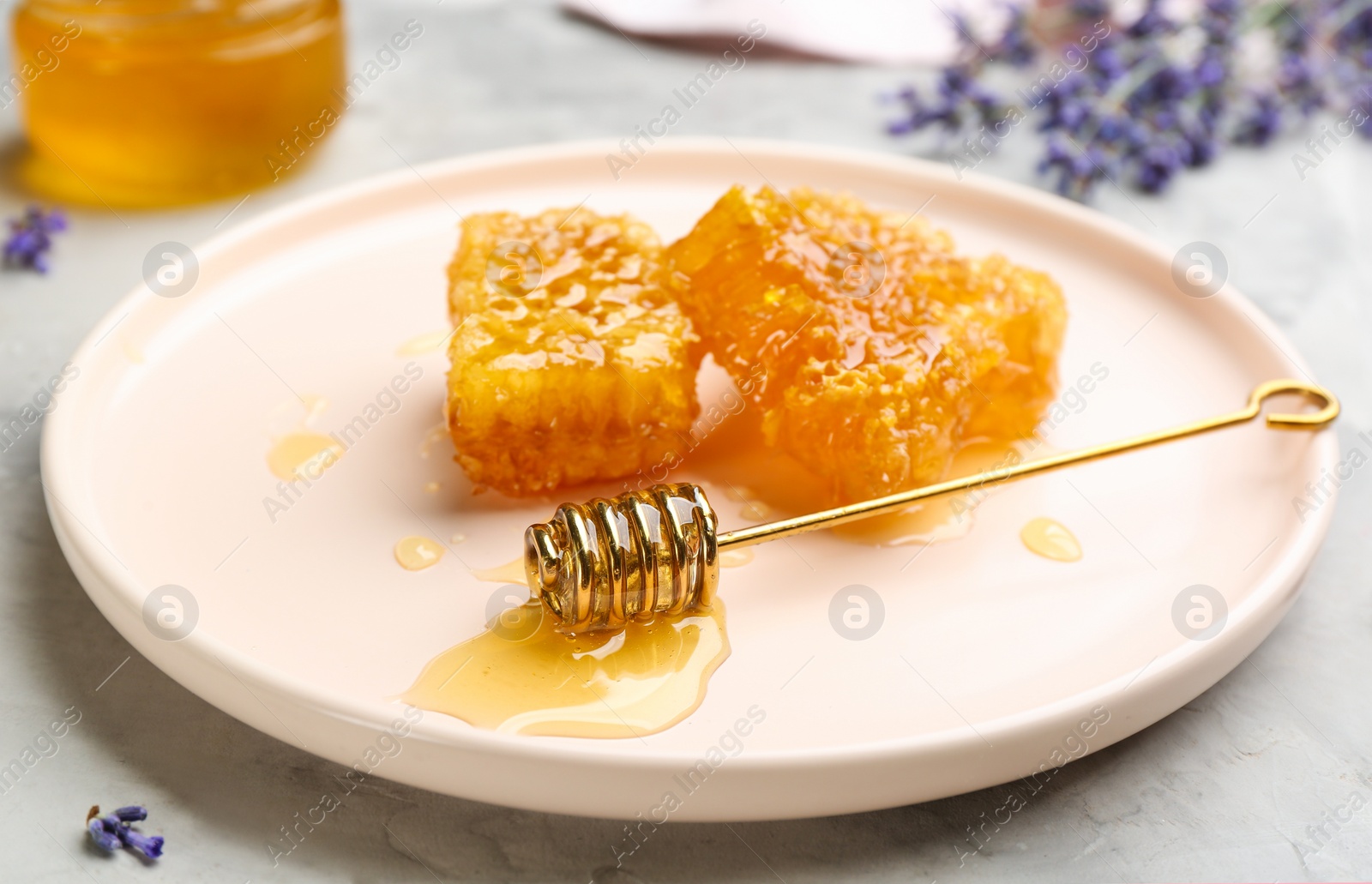 Photo of Honey combs and metal dipper on light grey table