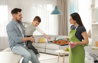 Photo of Woman treating family with oven baked buns in kitchen