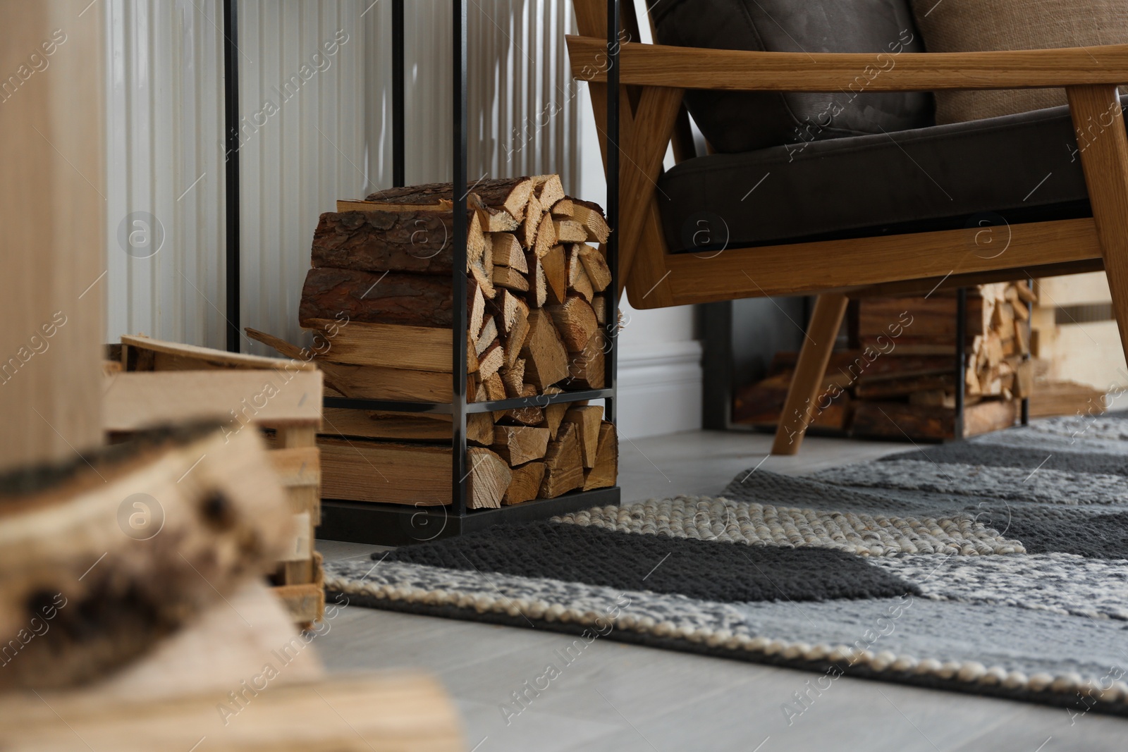 Photo of Firewood near armchair in stylish room interior