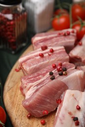 Photo of Cut raw pork ribs with peppercorns on table, closeup