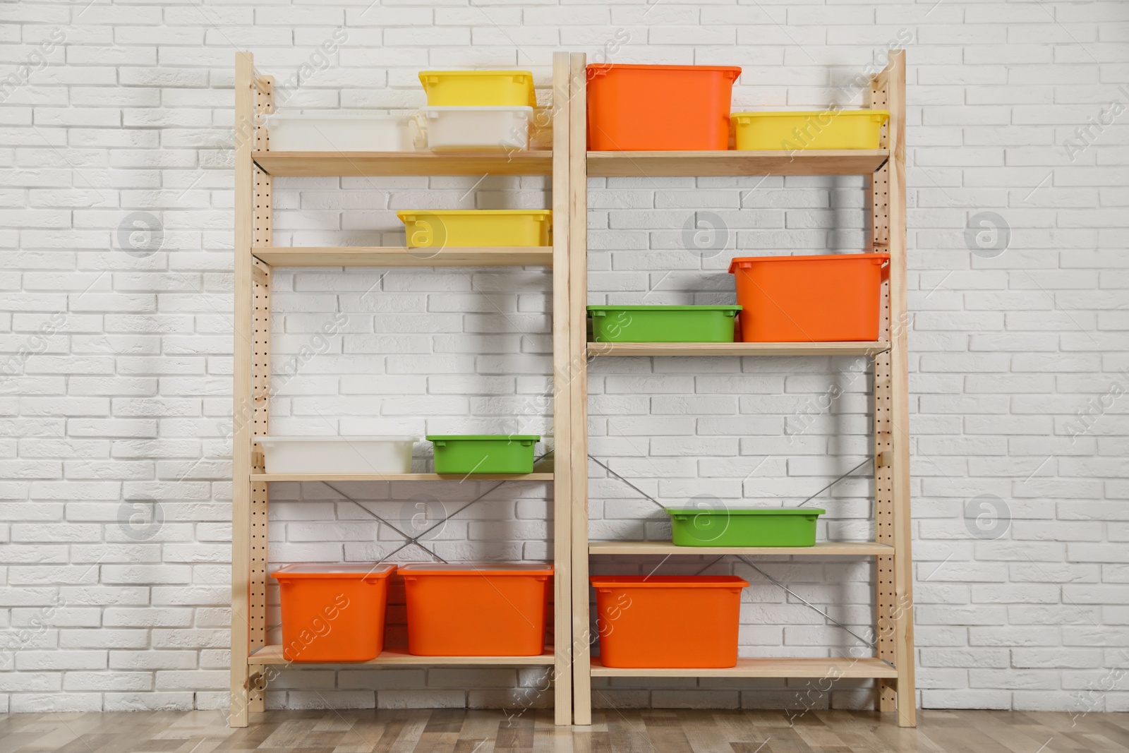 Photo of Wooden shelving units with colorful containers near white brick wall. Stylish room interior