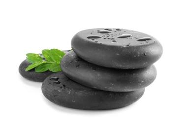 Spa stones and green leaves with water drops on white background