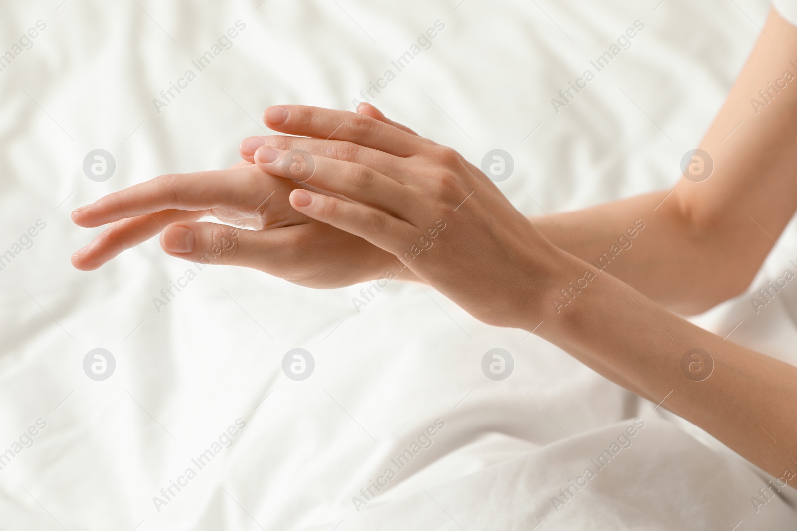 Photo of Woman applying hand cream in bed, closeup