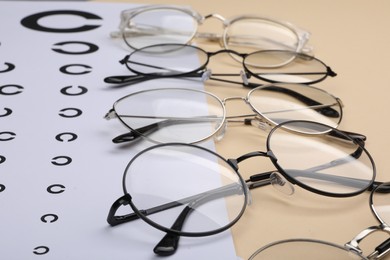 Vision test chart and glasses on beige background, closeup