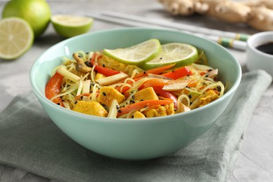 Photo of Stir-fry. Delicious cooked noodles with chicken and vegetables in bowl on table, closeup