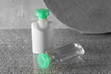 Photo of Mini bottles of cosmetic products on grey textured table