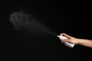 Photo of Nasal congestion. Woman spraying remedy from bottle on black background, closeup