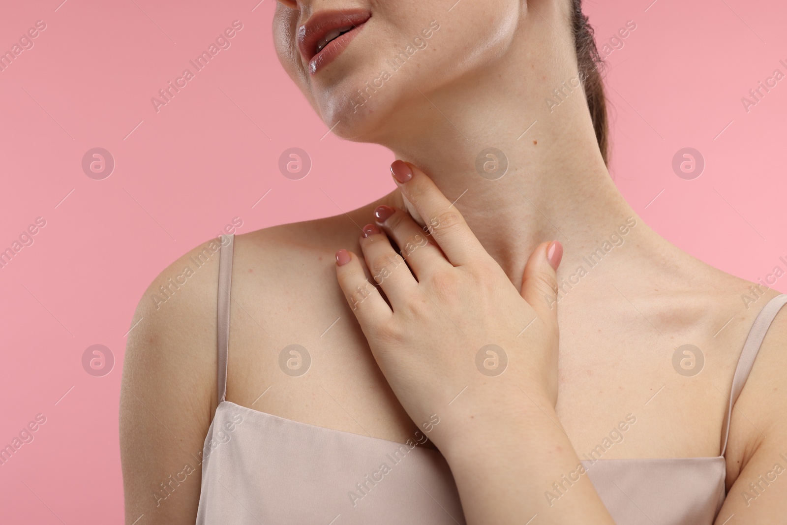 Photo of Woman touching her neck on pink background, closeup