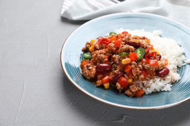 Photo of Plate of rice with chili con carne on light grey table, space for text