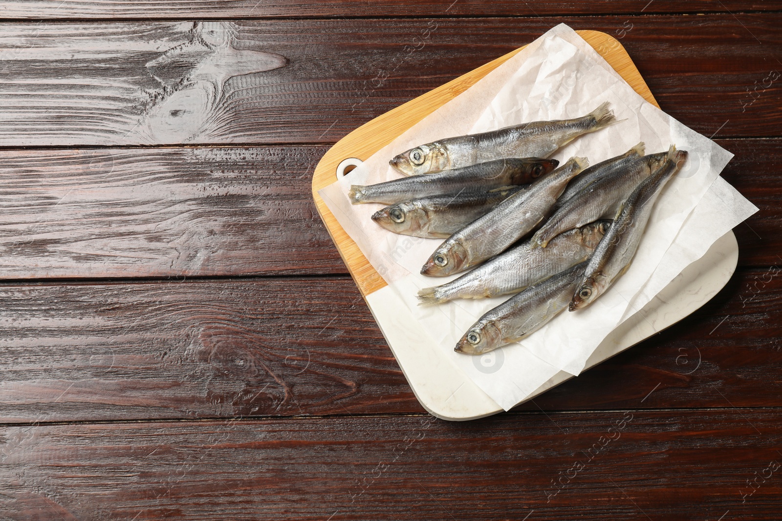 Photo of Fresh raw sprats on wooden table, top view. Space for text