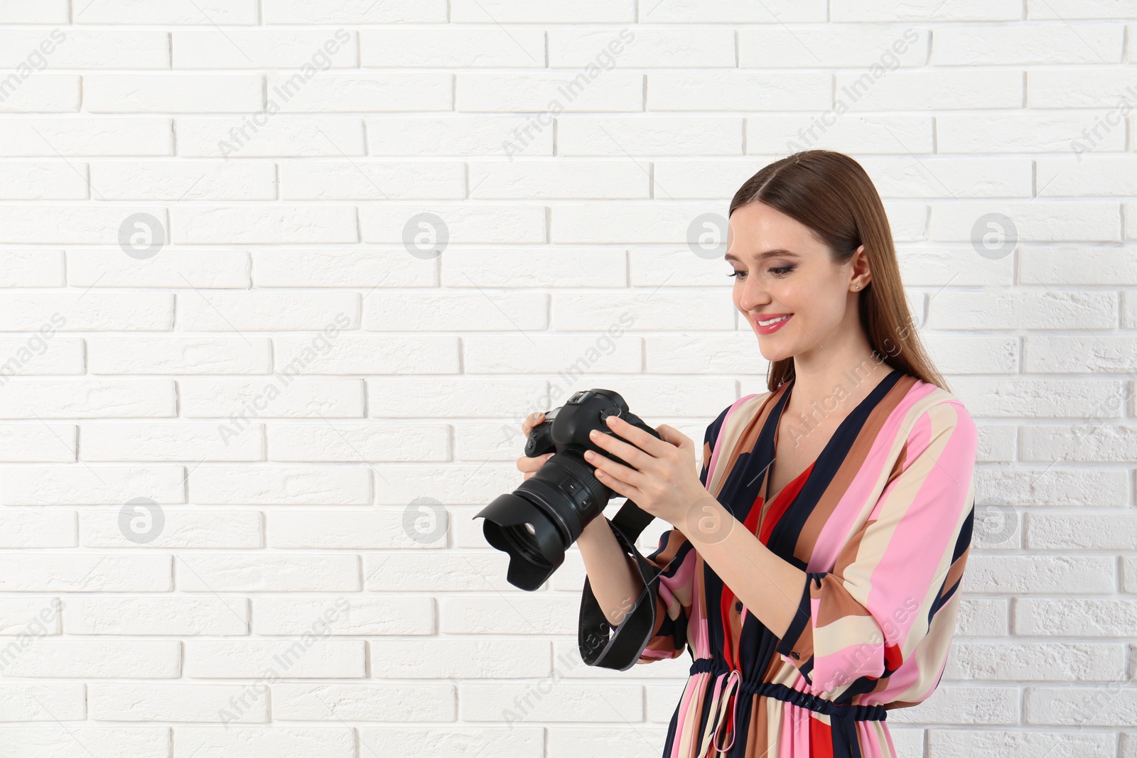 Photo of Professional photographer with modern camera near white brick wall. Space for text