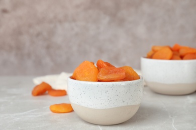 Photo of Bowl with apricots on grey table. Dried fruit as healthy food