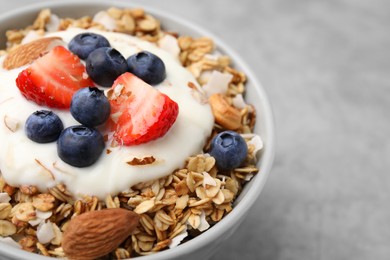 Photo of Tasty granola, yogurt and fresh berries in bowl on light grey table, closeup with space for text. Healthy breakfast