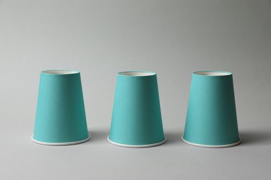 Photo of Three paper cups on light grey background. Thimblerig game