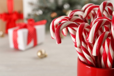Photo of Candy canes in cup on blurred background, space for text. Traditional Christmas treat