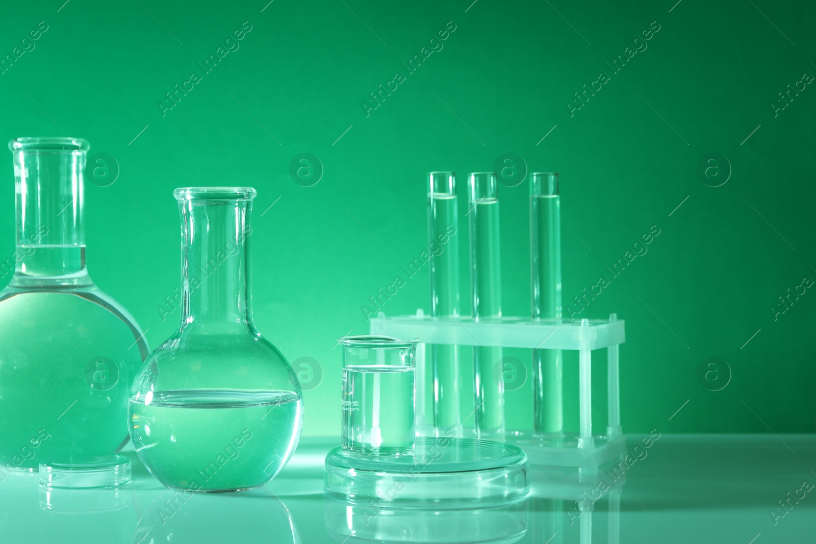 Photo of Laboratory analysis. Different glassware on table against green background