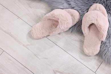 Pink soft slippers on light wooden floor at home, top view. Space for text