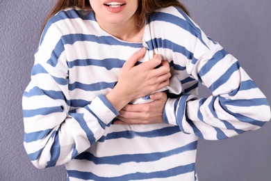 Photo of Young woman having heart attack on color background, closeup