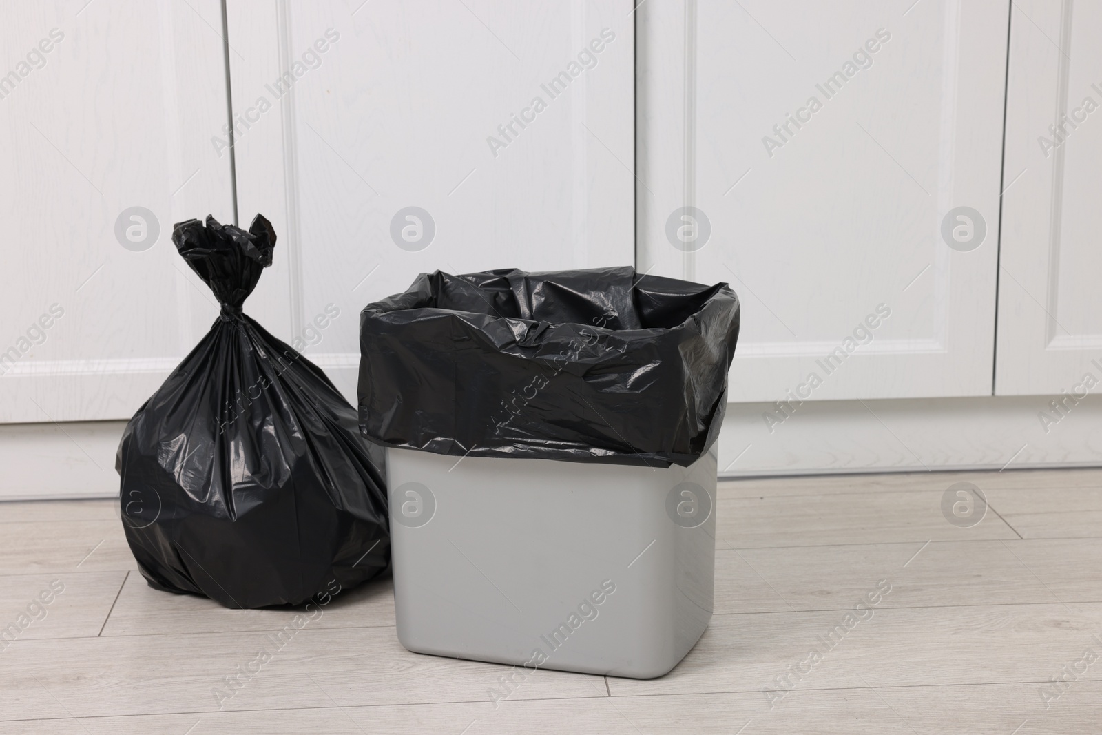 Photo of Plastic garbage bag and trash can indoors. Space for text