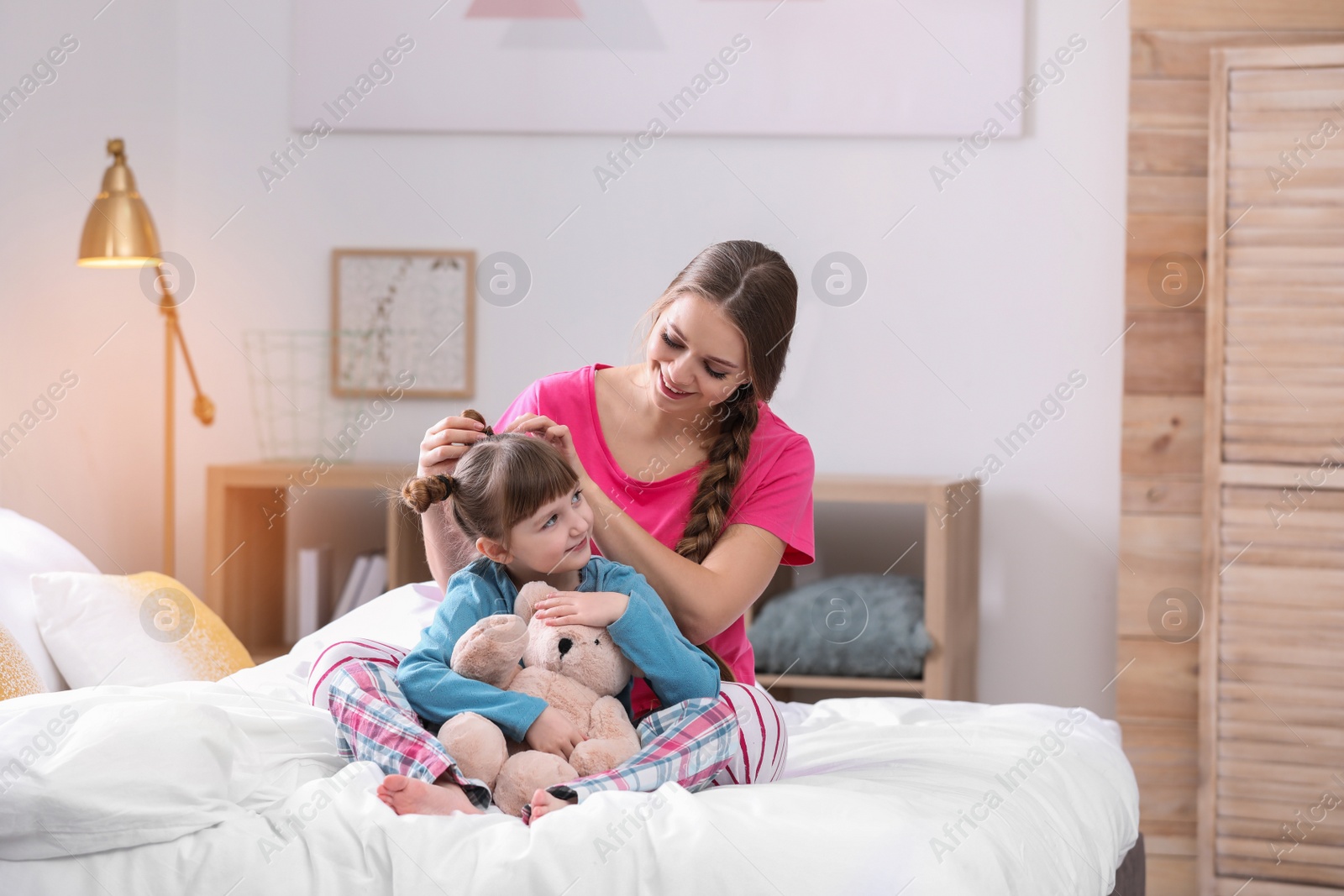 Photo of Happy woman and daughter in pajamas on bed at home