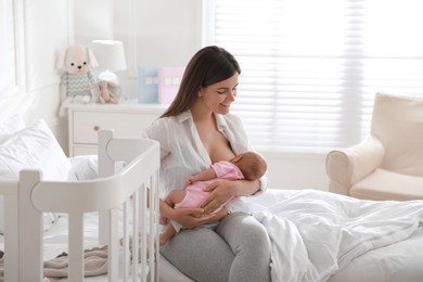 Photo of Happy young mother breastfeeding her newborn baby at home