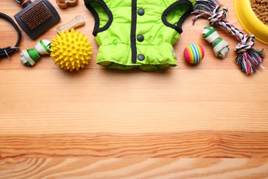 Photo of Flat lay composition with dog clothes, food and accessories on wooden table. Space for text