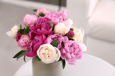 Photo of Vase with bouquet of beautiful peonies on table in room, space for text