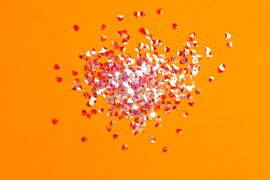 Pile of shiny glitter on orange background, flat lay