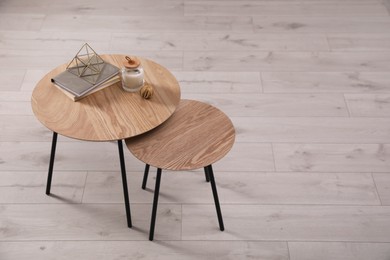 Photo of Wooden nesting tables with books and decor indoors